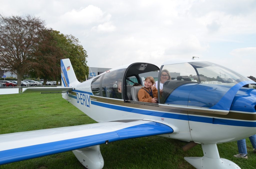 Lächelndes Mädchen sitzt mit der Pilotin im Motorflugzeug Robin vor dem Rundflug
