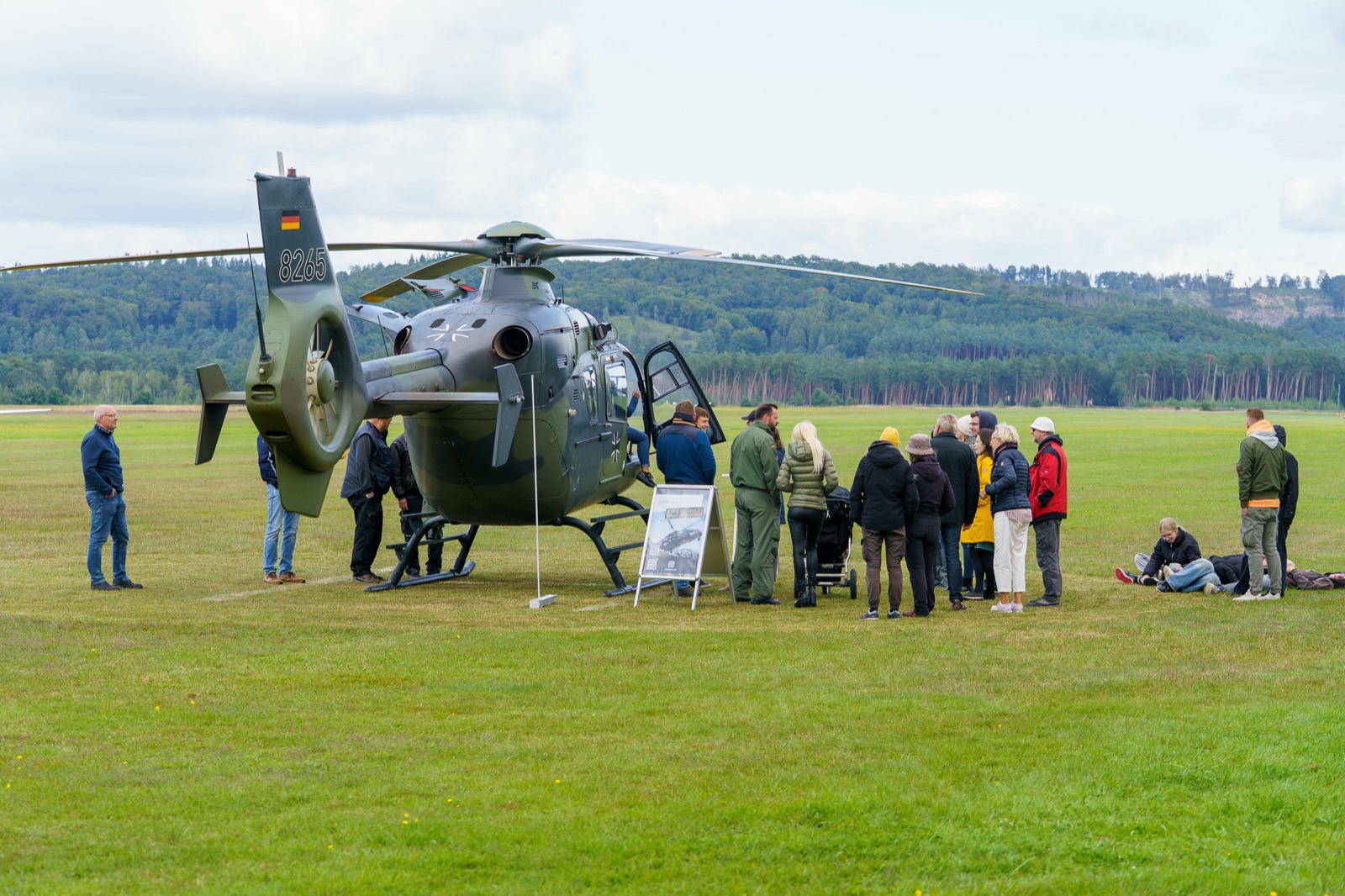 Hubschrauber EC 135 der Bundeswehr auf einem Segelfluggelände, Besucherinnen und Besucher schauen sich die Maschine an