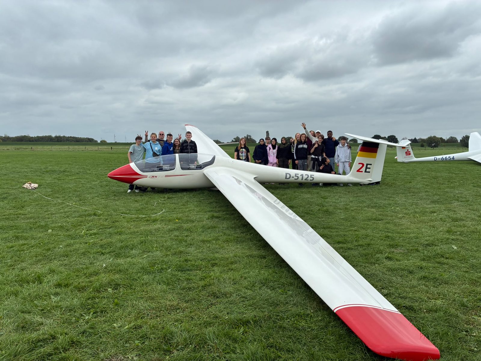 Schülerinnen und Schüler der Gesamtschule Emmerich vor einem Segelflugzeug auf dem Segelfluggelände Emmerich-Palmersward