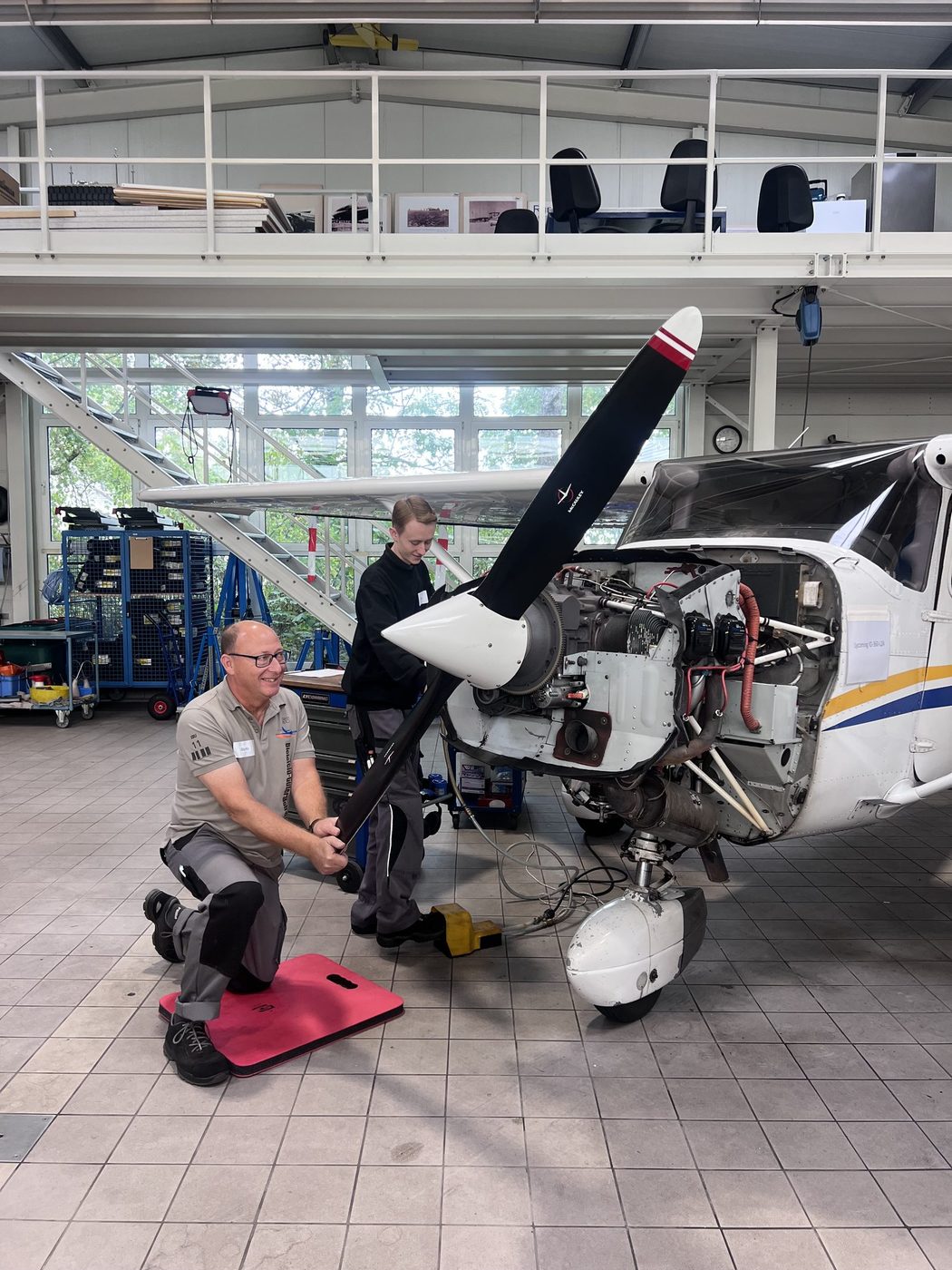 Referent erklärt am geöffneten Motorraum der Cessna 172 R den Lycoming-Motor
